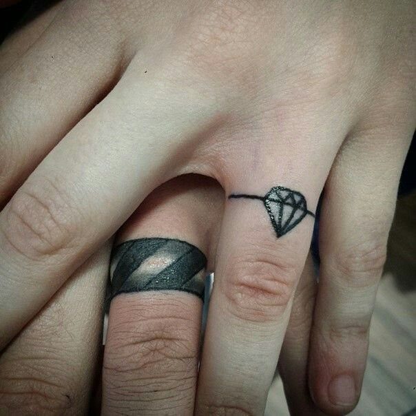 Diamond ring tattoo and black band tattoo on two ring fingers.
