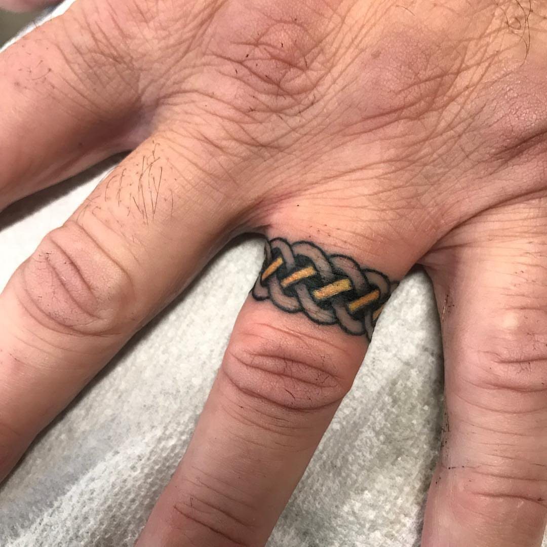 Braided knot wedding ring tattoo on a person's ring finger.
