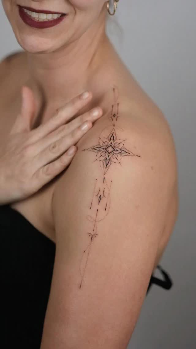 Woman's shoulder with a geometric black ink star tattoo and fine line details.