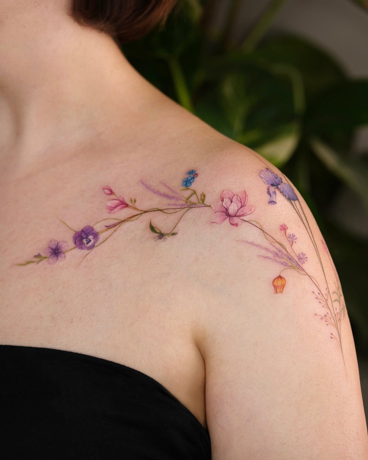 Watercolor floral tattoo with purple and pink flowers on a woman's shoulder