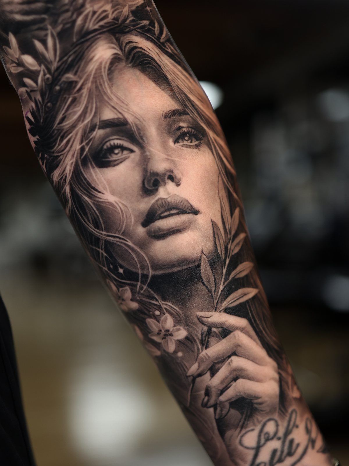 Detailed realism tattoo of a woman's face on a shoulder and upper arm.