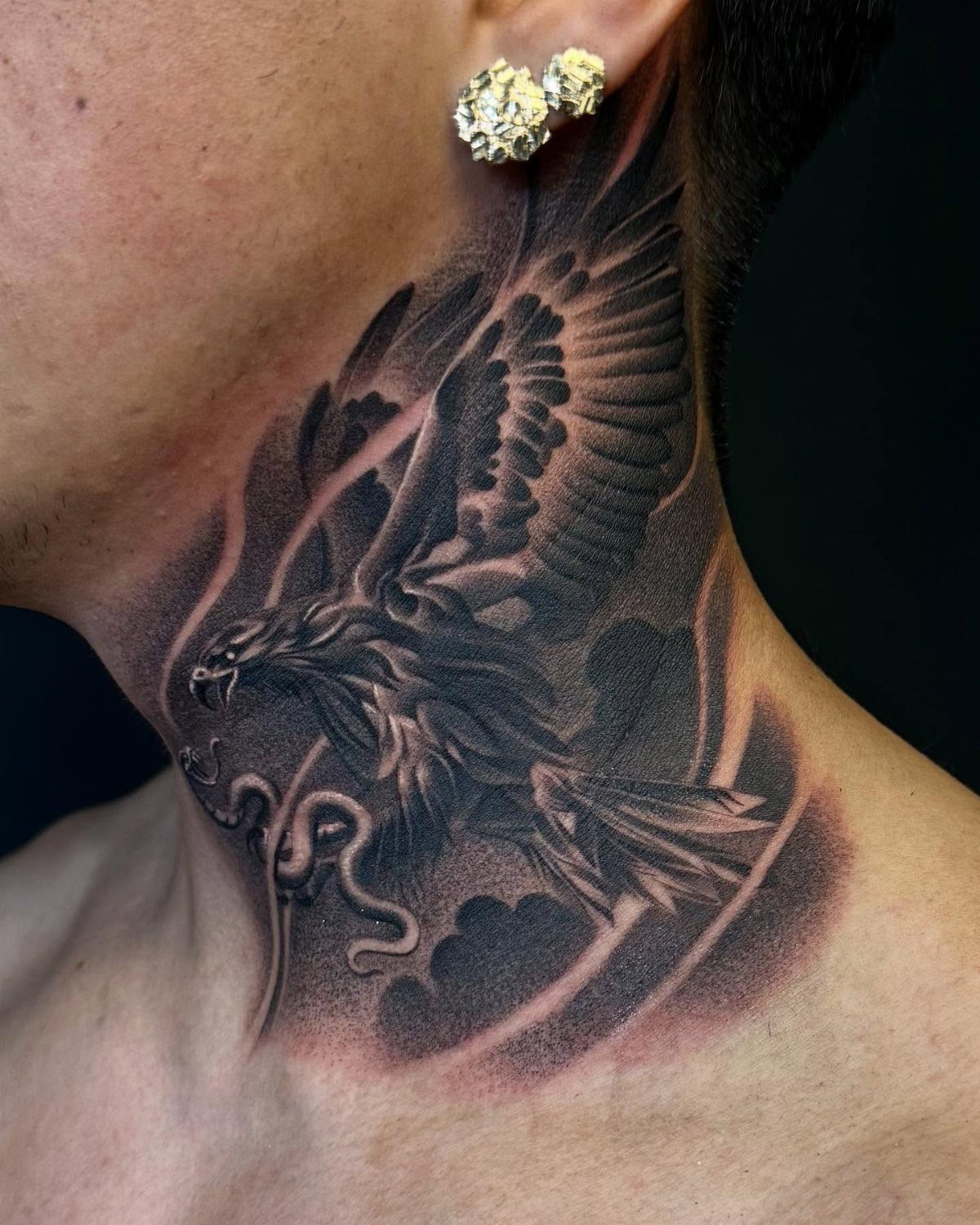 Eagle tattoo with spread wings and clouds on a person's side neck.