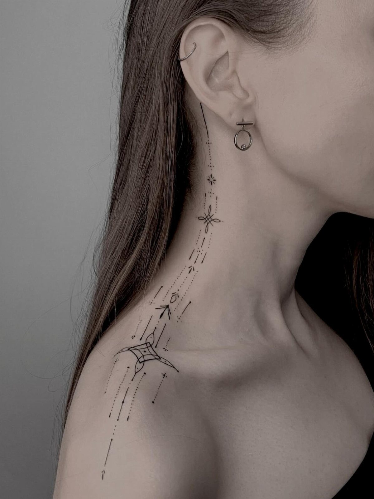 Fine line geometric tattoo with dots and stars on a person's side neck.