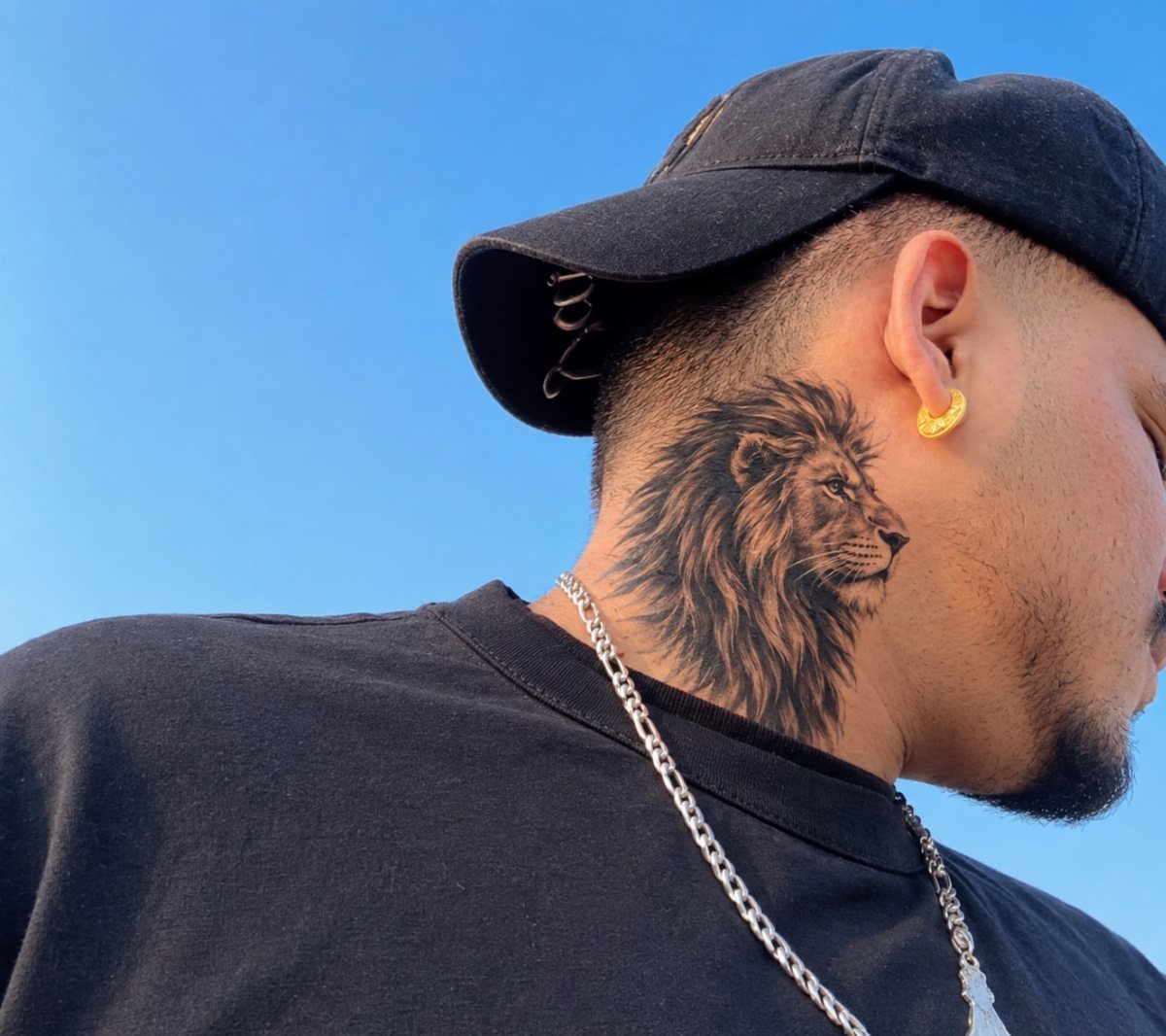 Lion tattoo on the side of a man's neck with a black cap.