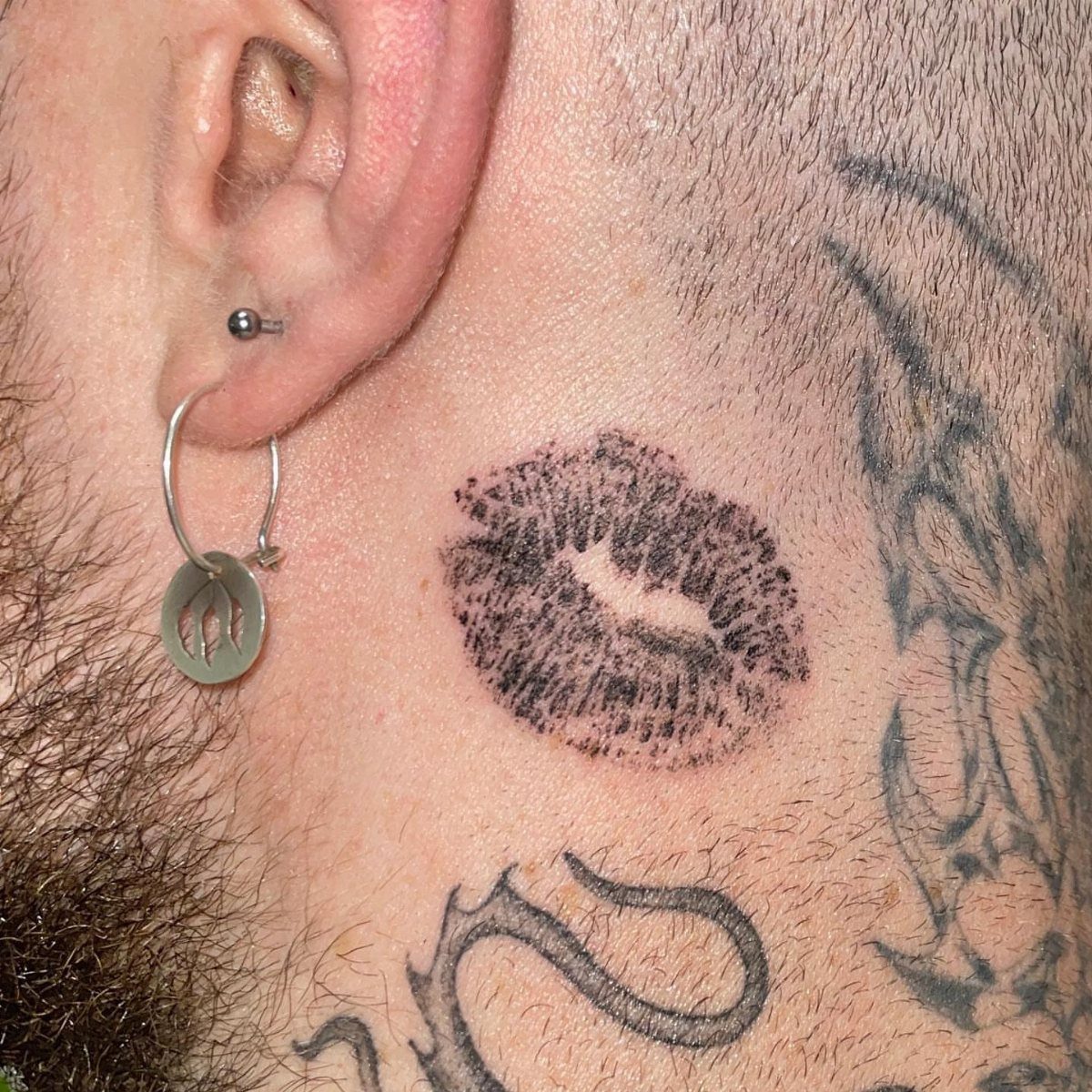 Lip print kiss tattoo on the side of a man's neck.