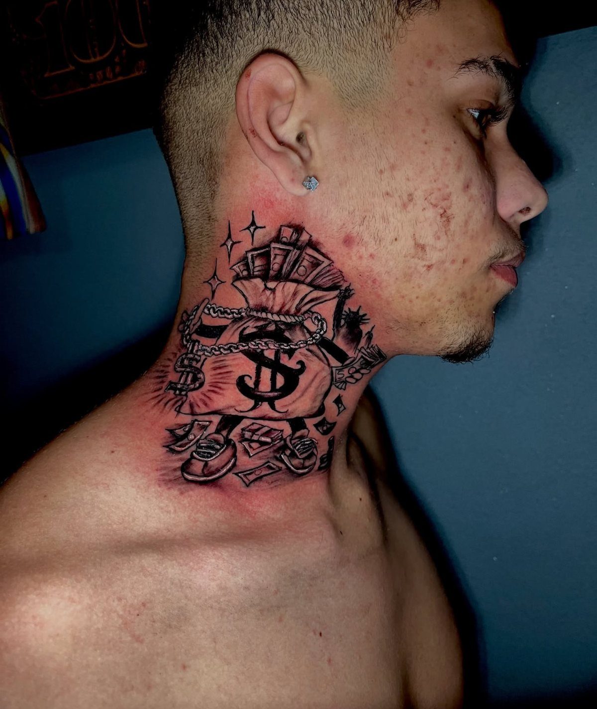 Man with a detailed money bag and dollar sign tattoo on his side neck.