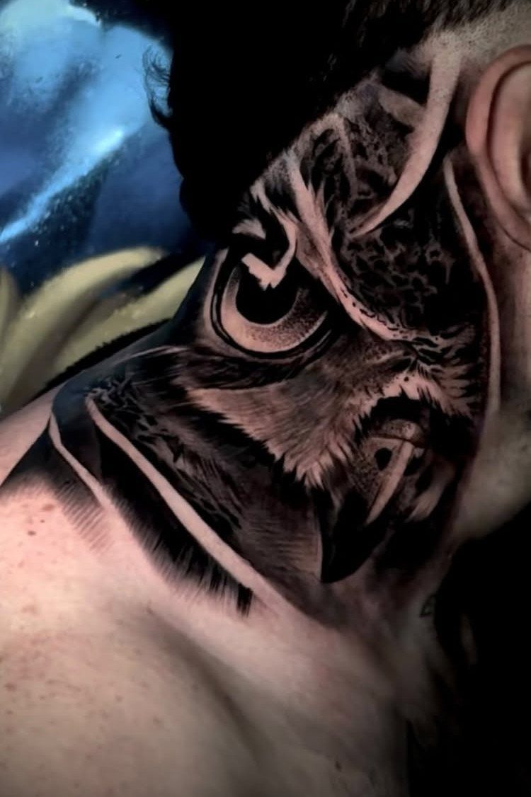 Detailed black and grey owl tattoo on the side of a person's neck.