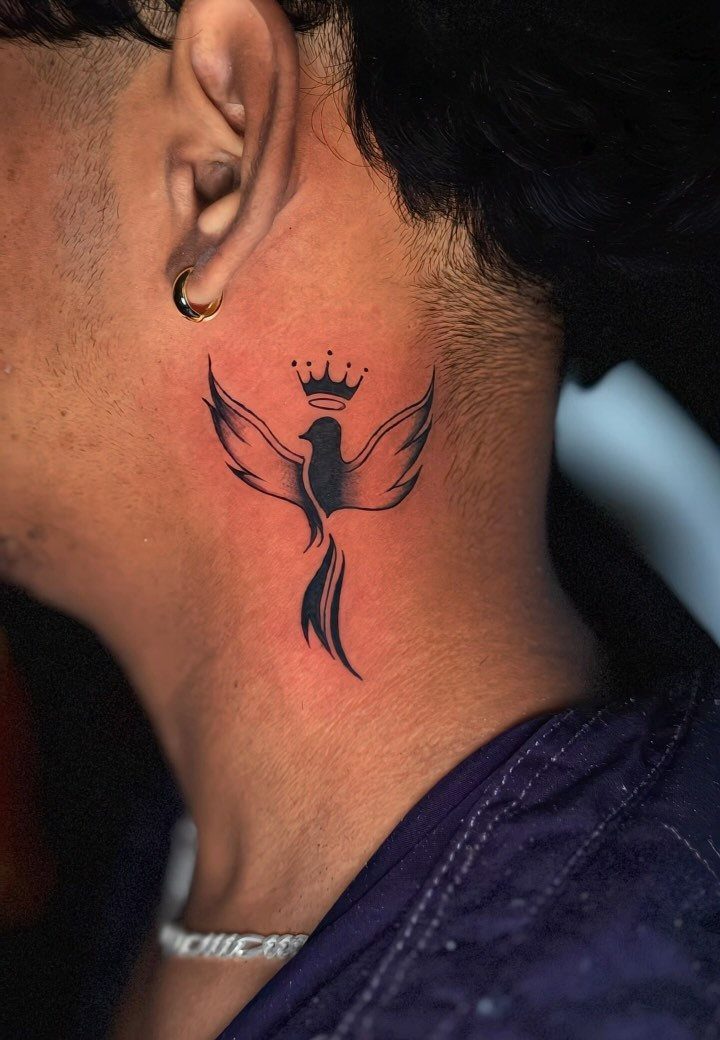 Stylized black bird tattoo with a crown on the side of a neck