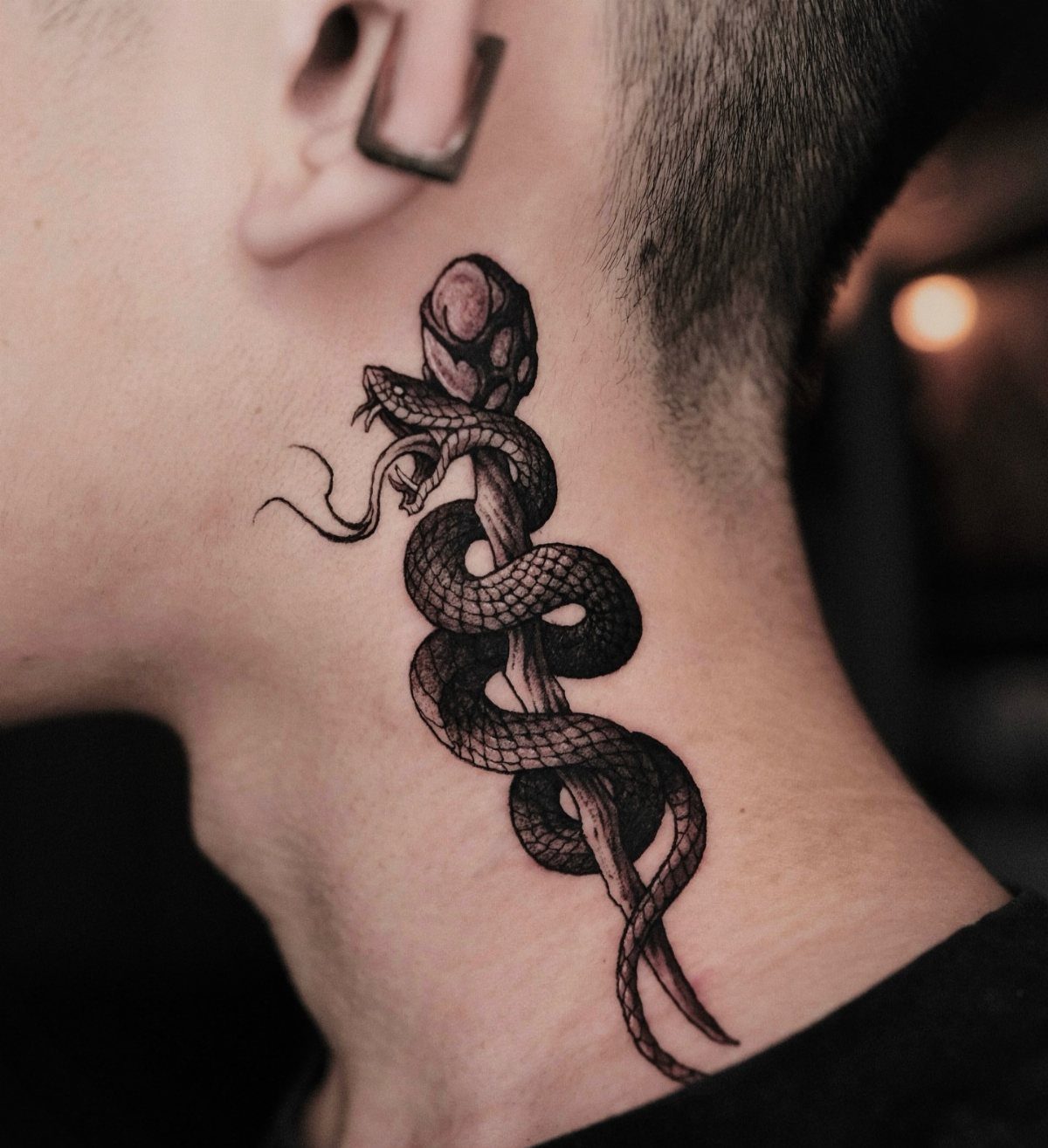 Coiled snake tattoo on the side of a person's neck with a crystal.