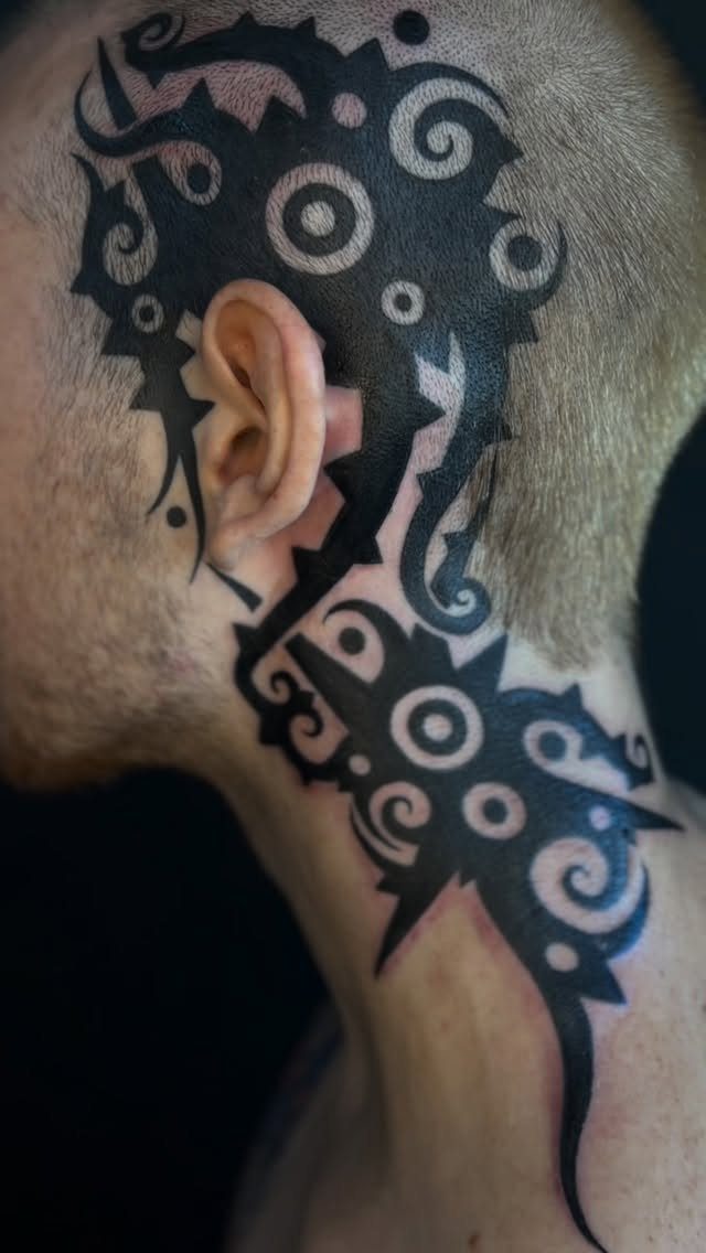Bold black tribal tattoo with swirls on the side of a man's neck