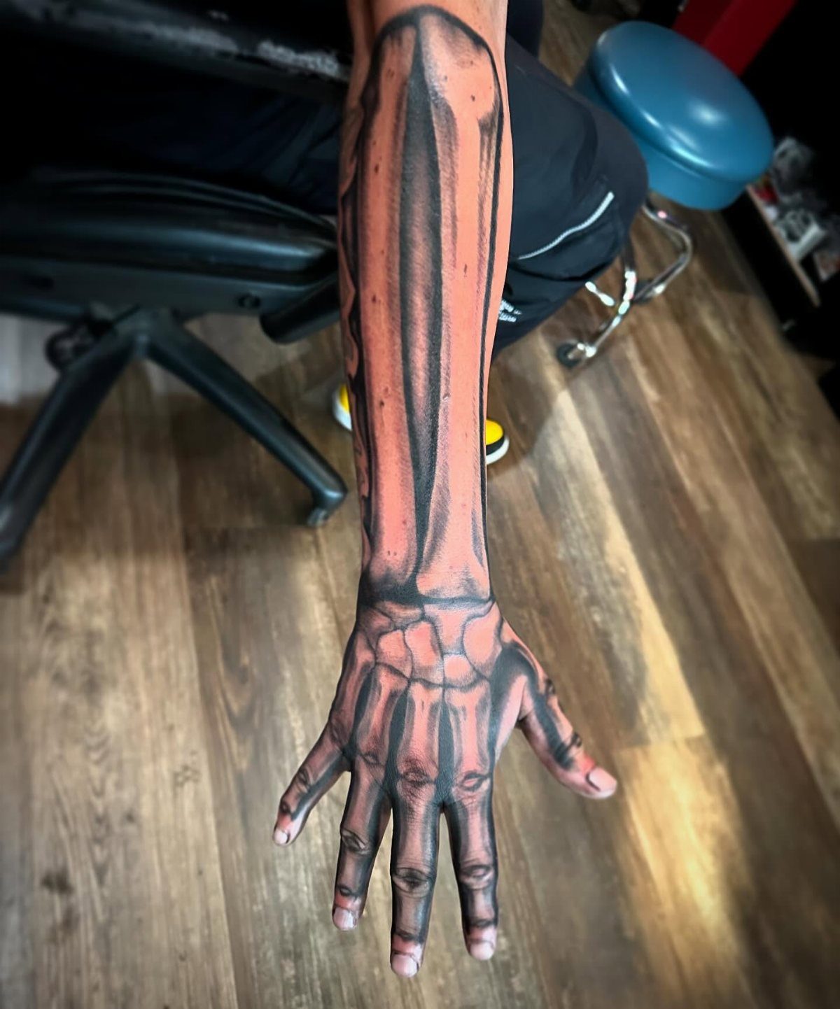 Skeleton arm and hand tattoo extending from the forearm to the fingertips.