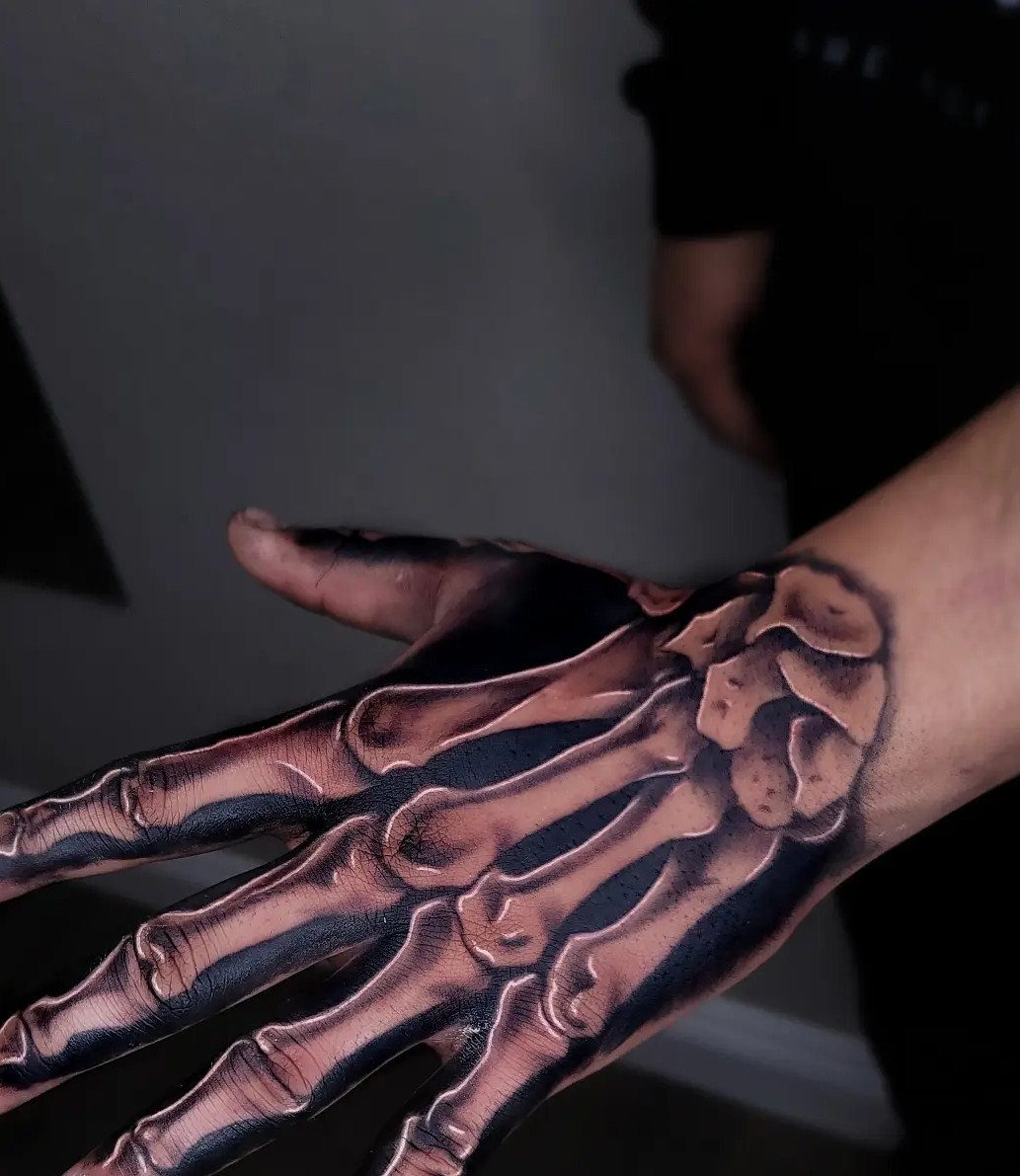 Realistic skeleton hand tattoo on the back of a person's hand with detailed shading