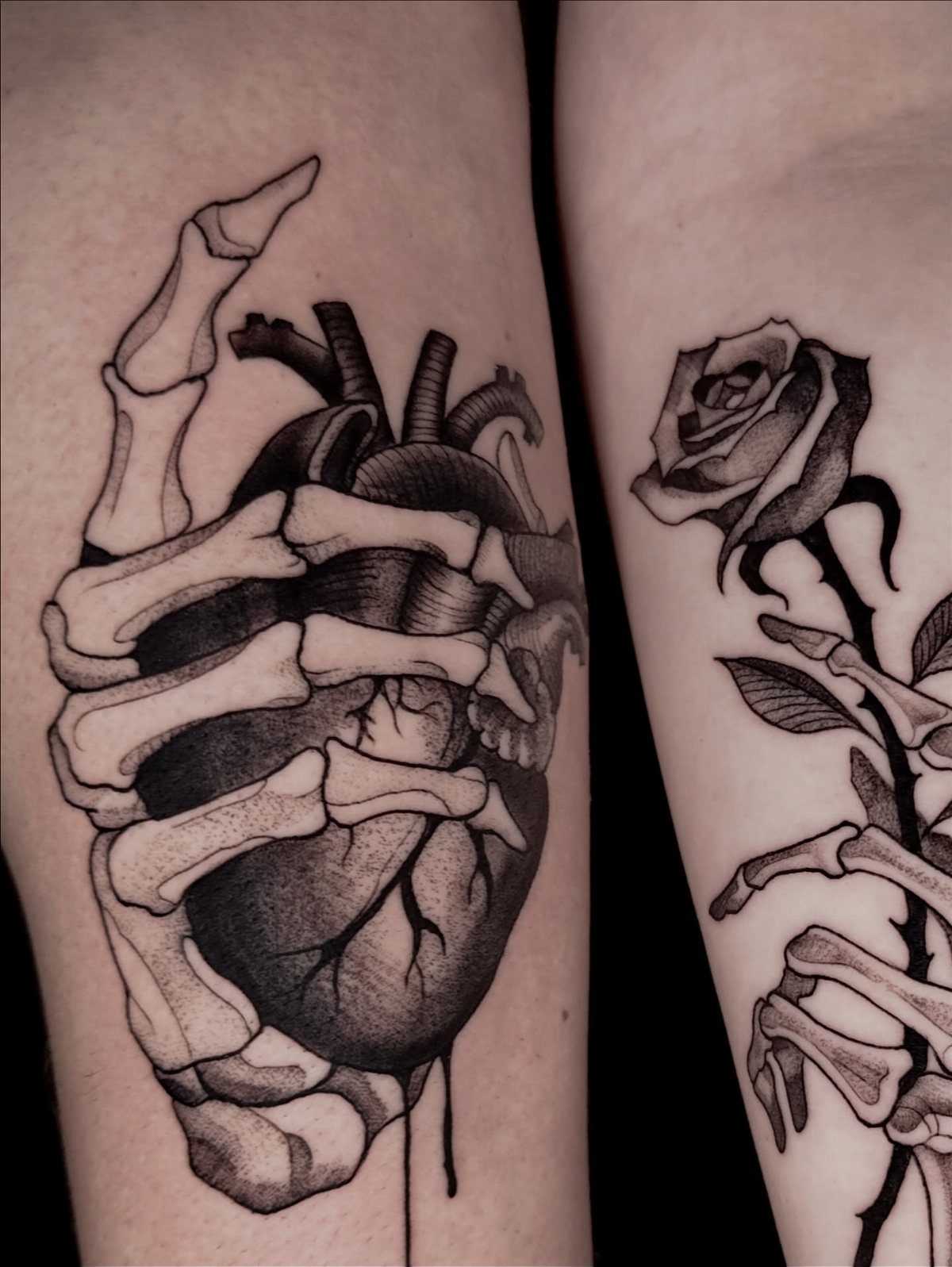 Skeletal hand tattoo clutching an anatomical heart on a person's skin.