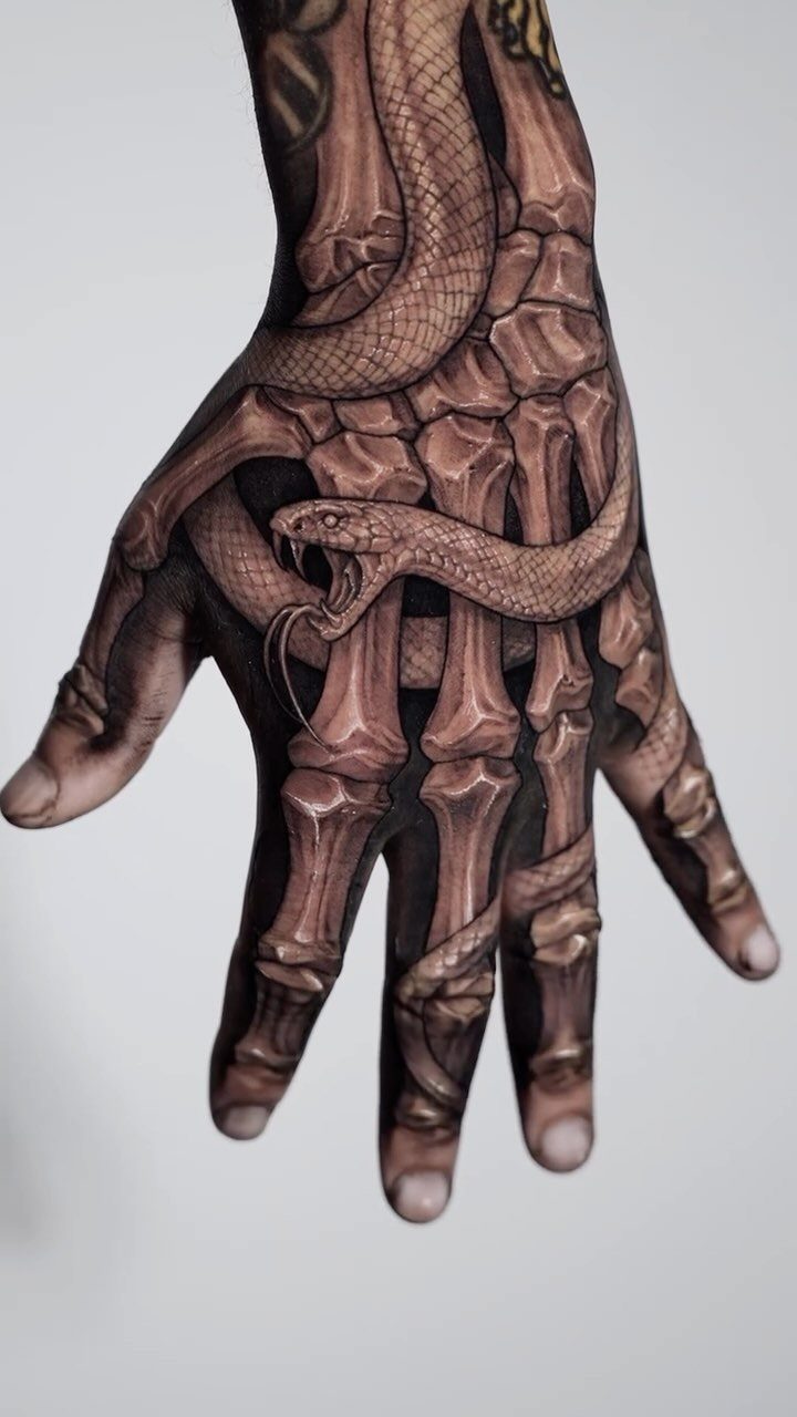 Skeleton hand tattoo with a snake coiled around the finger bones and wrist.