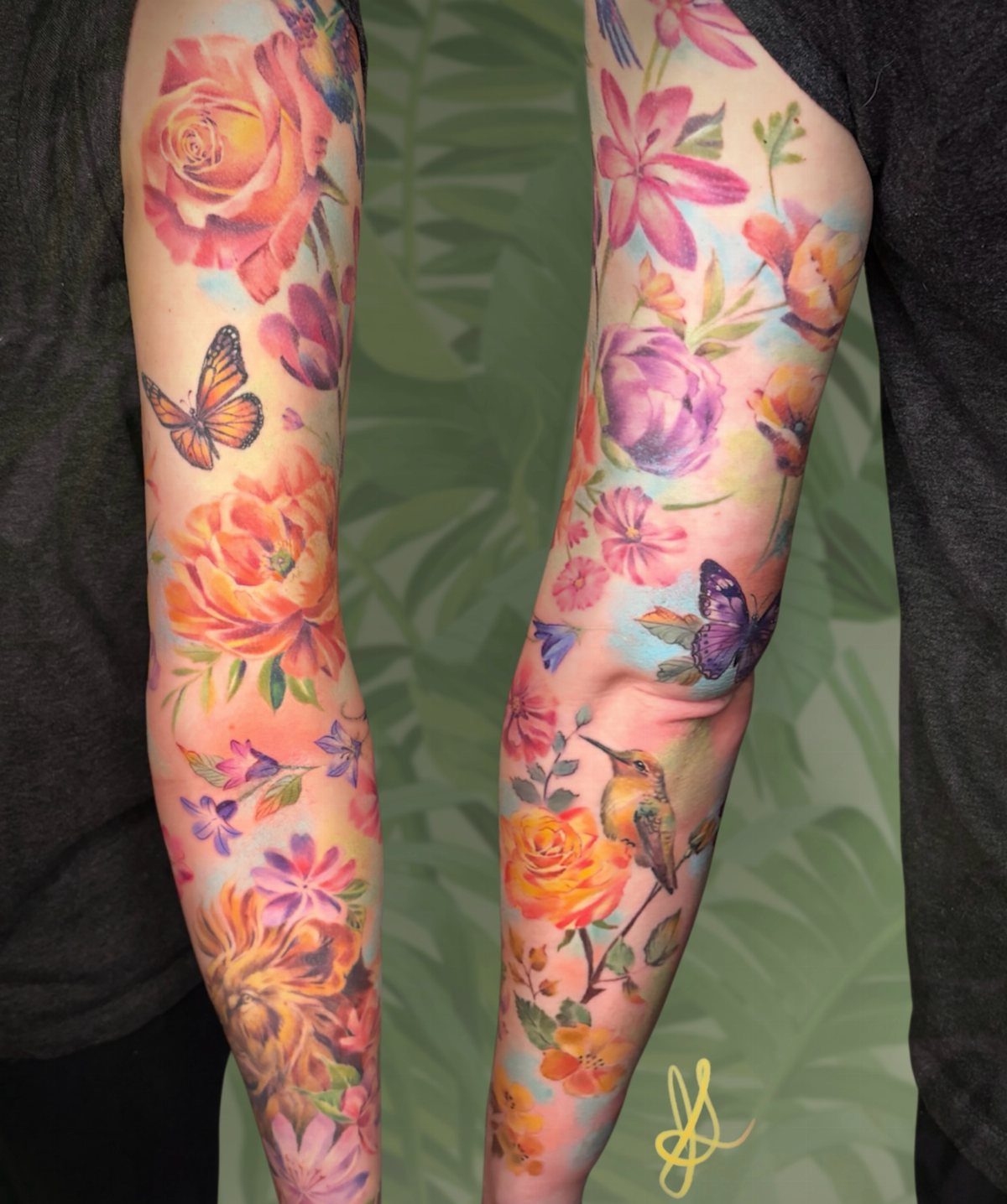 Watercolor sleeve tattoos on arms featuring colorful flowers, butterflies, and a hummingbird.