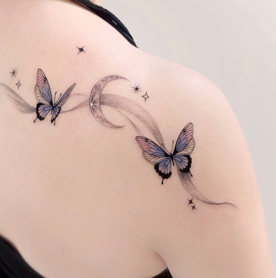 Butterfly and crescent moon tattoo with stars on a person's shoulder.