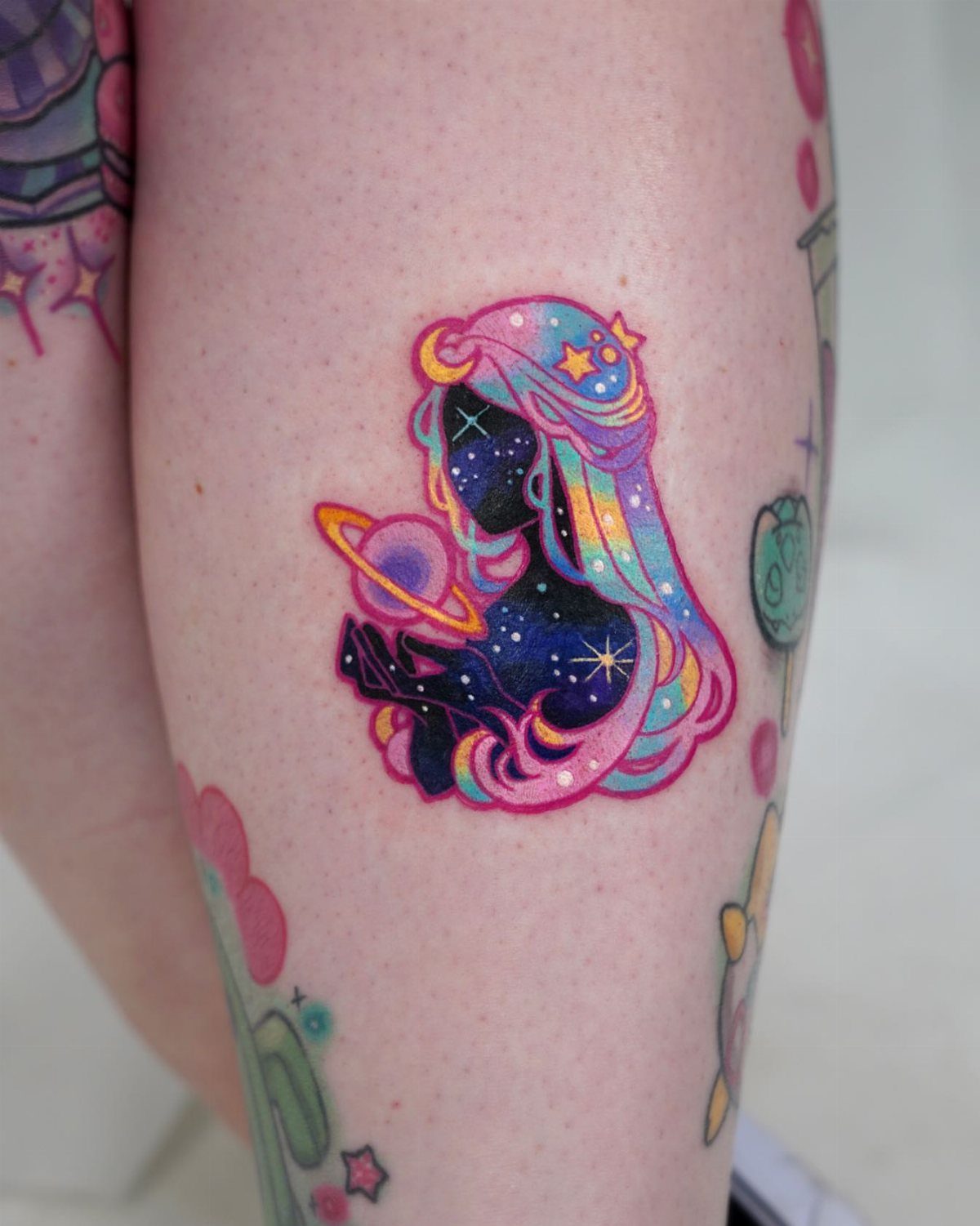 Celestial tattoo of a woman's silhouette filled with stars, moon, and a planet.