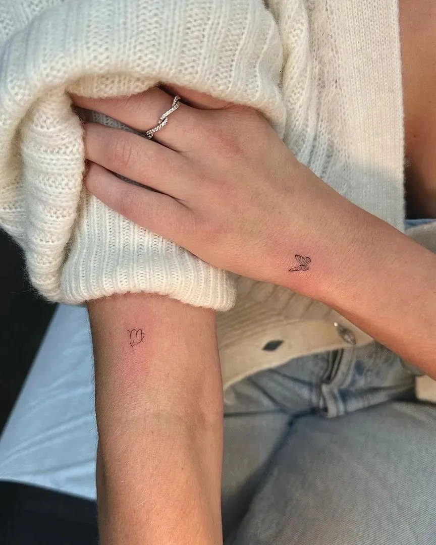 Small red zodiac symbol and bird tattoos on a person's inner wrists