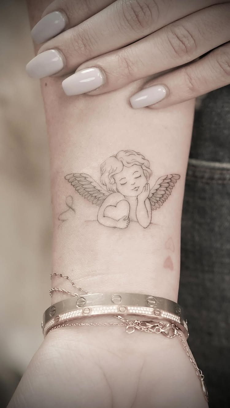 Sleeping angel tattoo on a wrist with gold bracelets and manicured nails