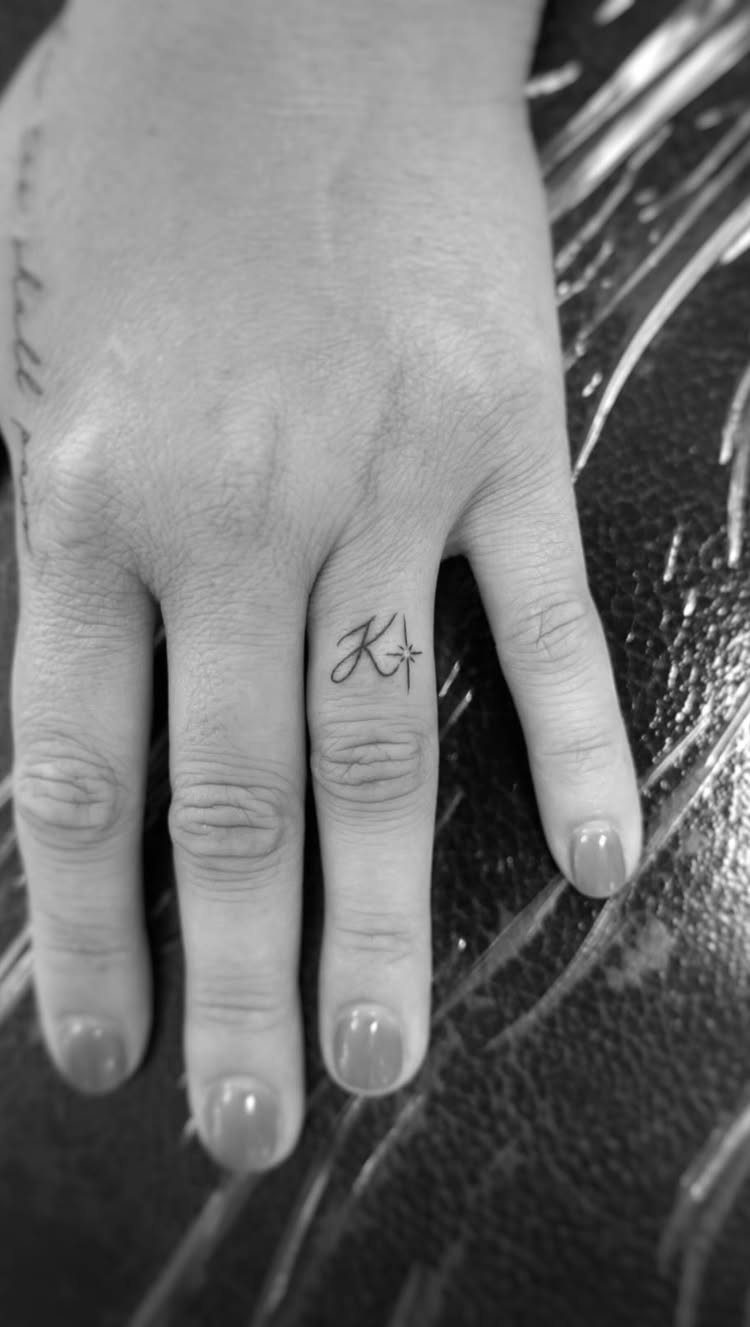 Hand with a small letter K and star tattoo on the middle finger