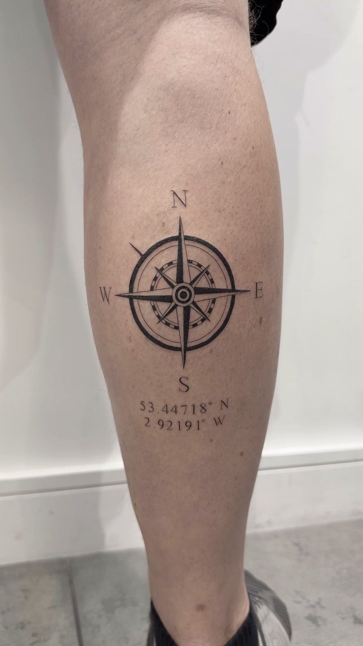 Compass rose tattoo with geographic coordinates on a person's lower leg