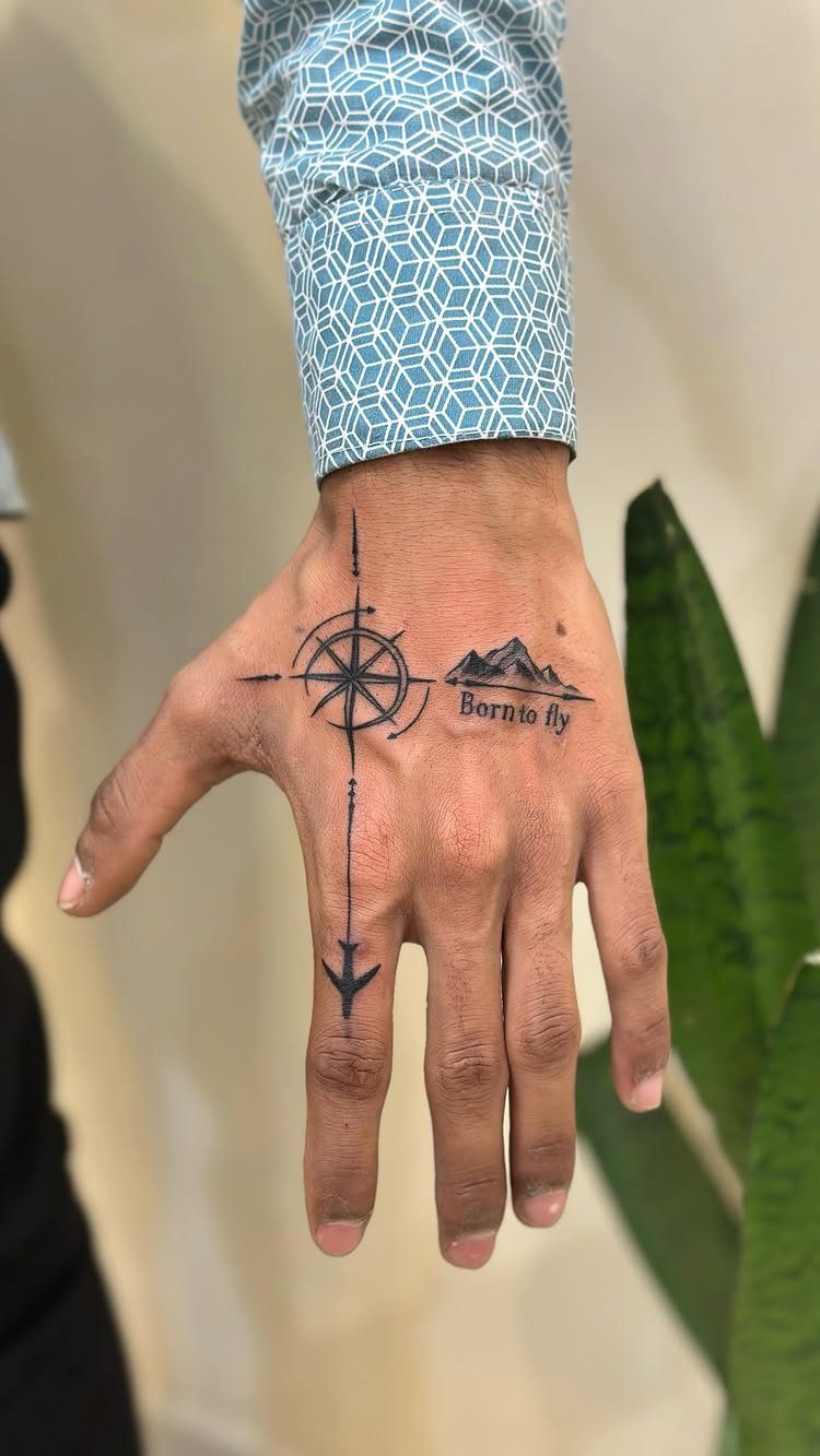 Man's hand and wrist with a compass and mountain tattoo design