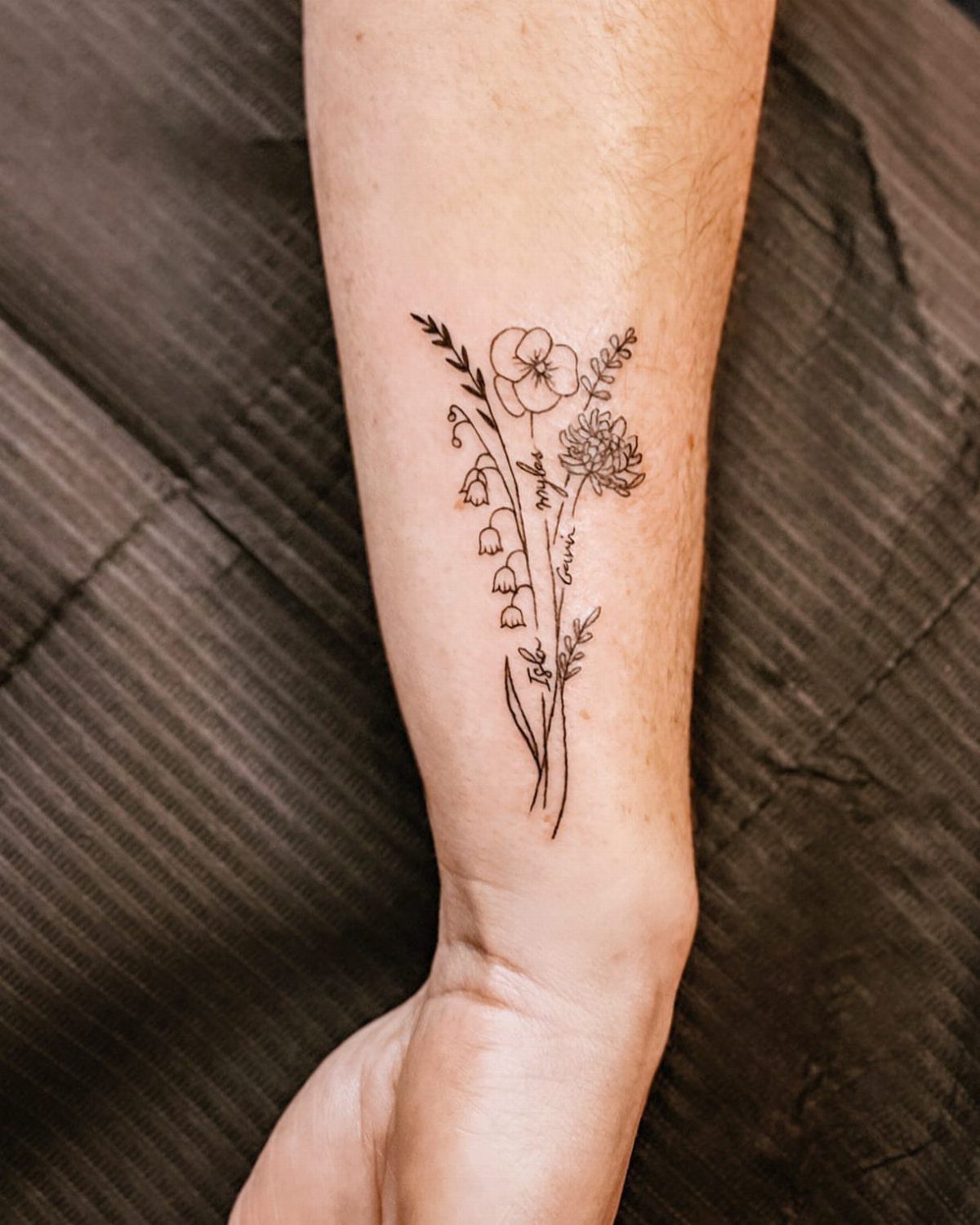 Floral bouquet tattoo on the inner forearm and wrist of a person.