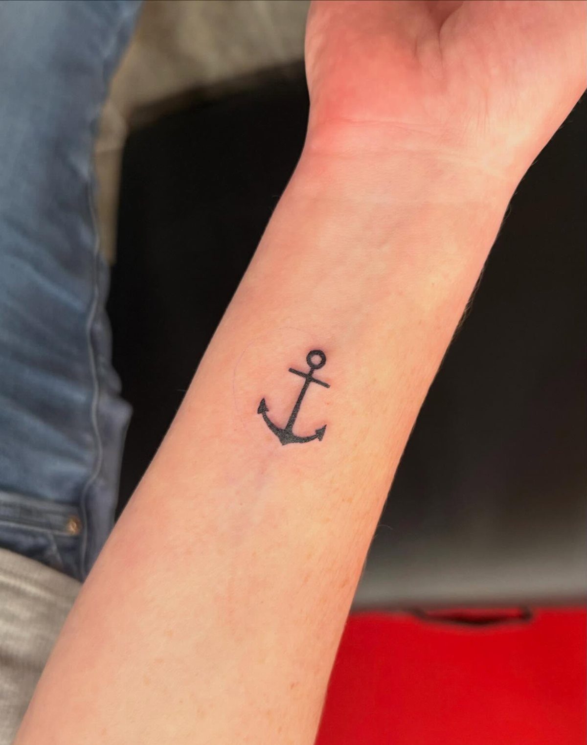 Small black anchor tattoo on the inner wrist of a person's arm.