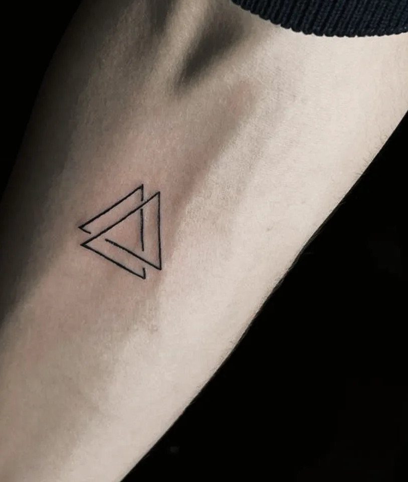 Small geometric tattoo of overlapping triangles on a person's inner wrist.