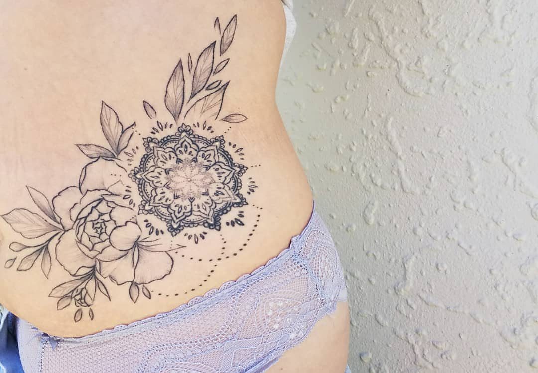 Mandala and flower tattoo on a woman's lower stomach and hip area