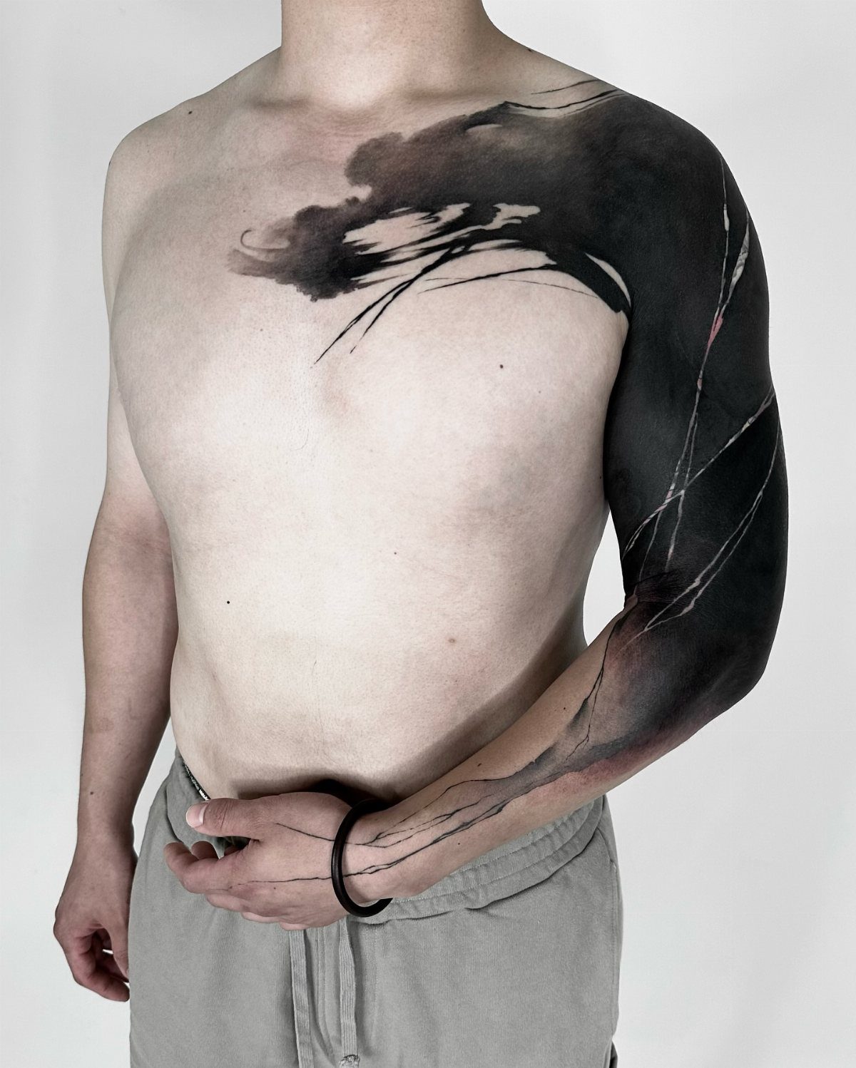 Man with a large black ink abstract tattoo on his arm and chest