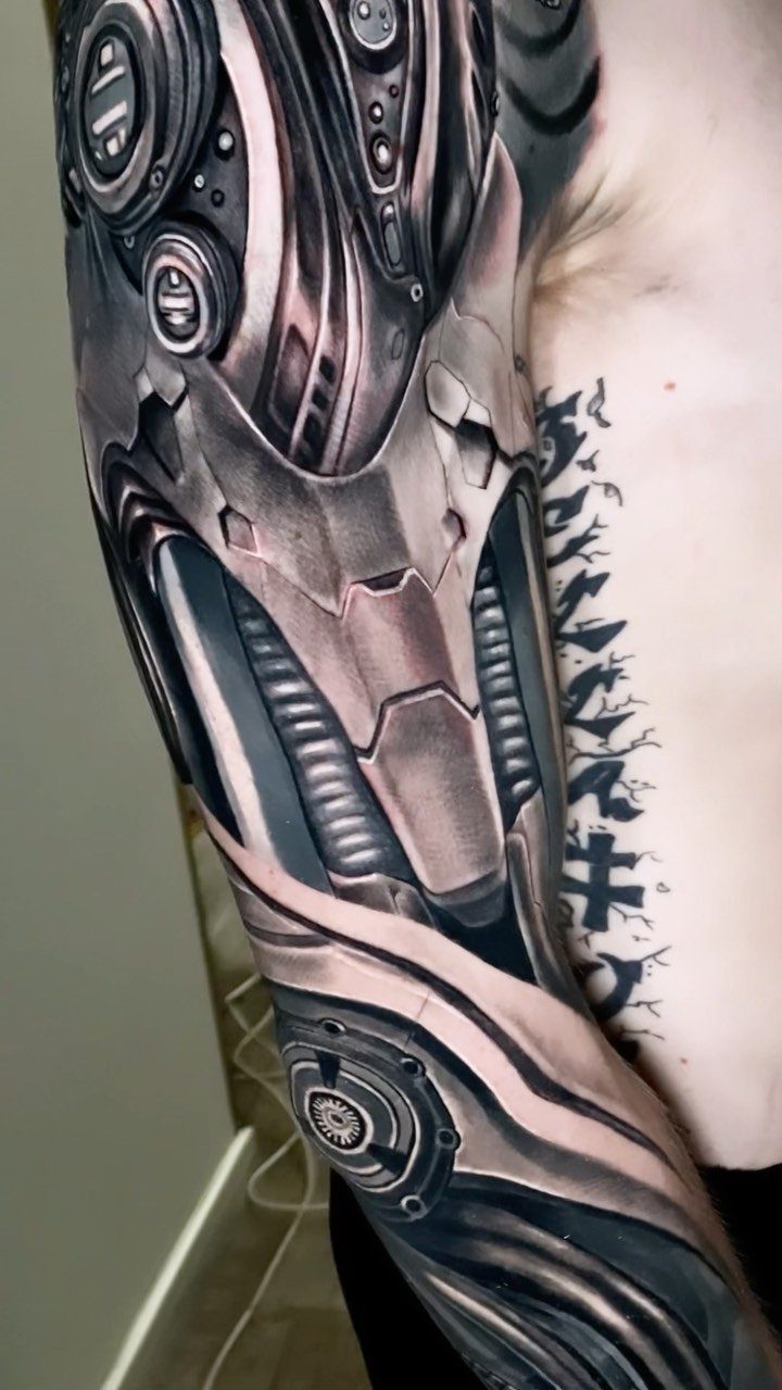 Biomechanical tattoo on an arm showing detailed metallic plates and mechanical components.
