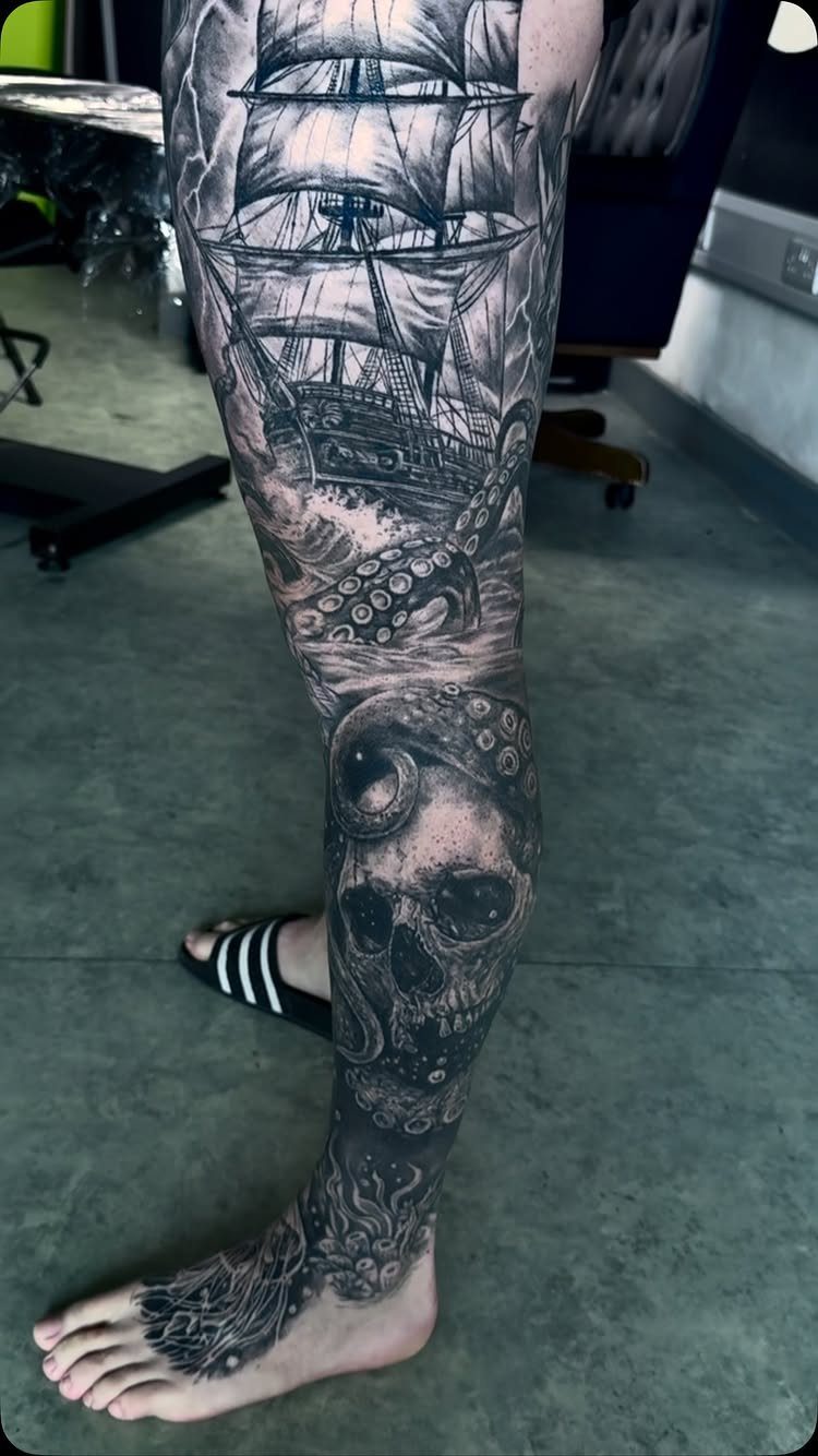 Detailed black ink leg tattoo featuring a sailing ship, octopus, and a skull.