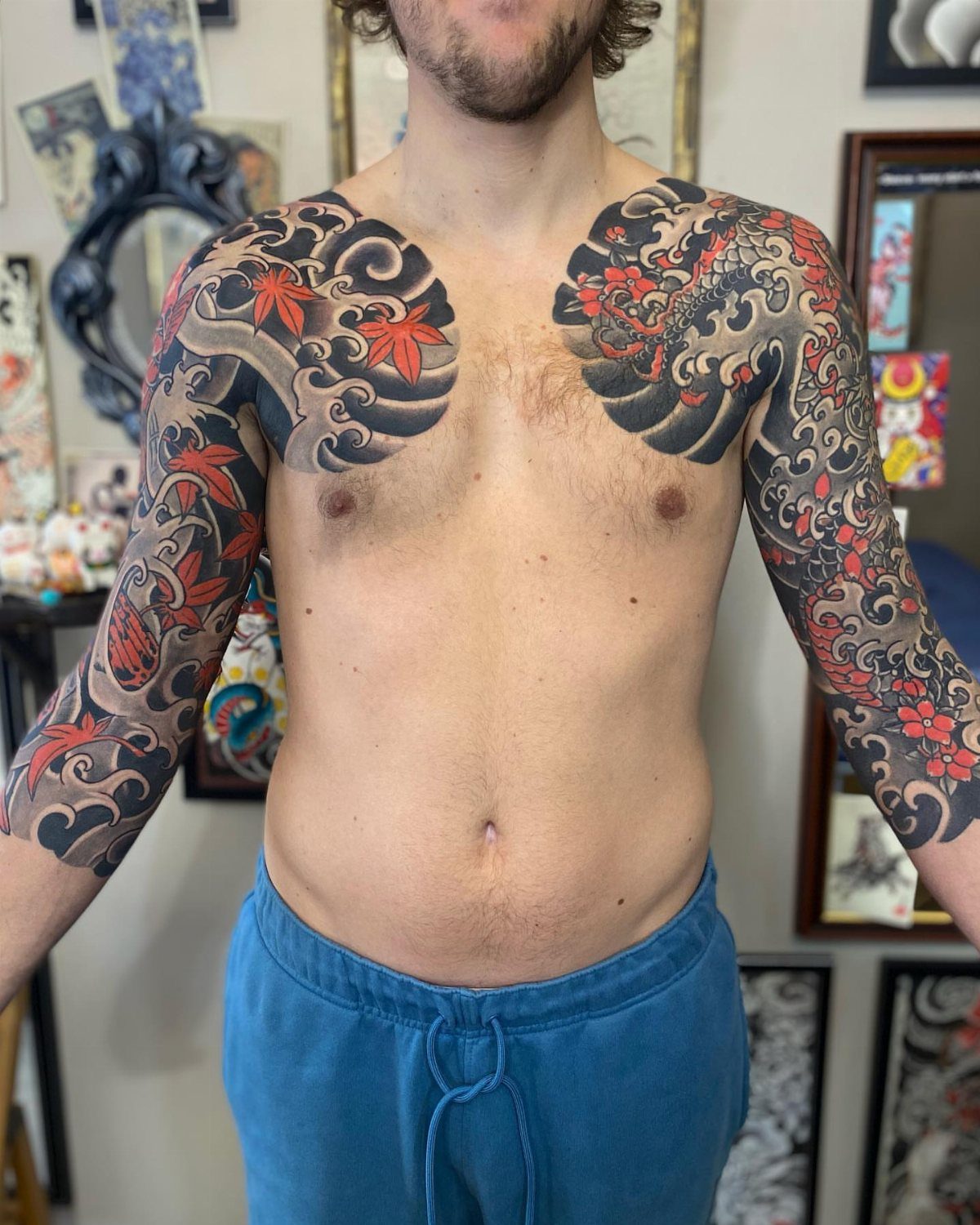 Man with traditional Japanese body art tattoos featuring waves and red maple leaves.