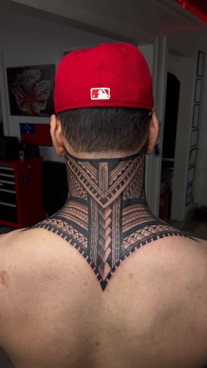 Man's neck and upper back featuring a bold black ink tribal tattoo design.