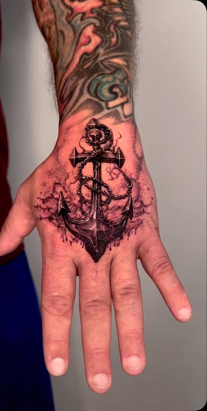 Detailed anchor tattoo with rope on the back of a person's hand.