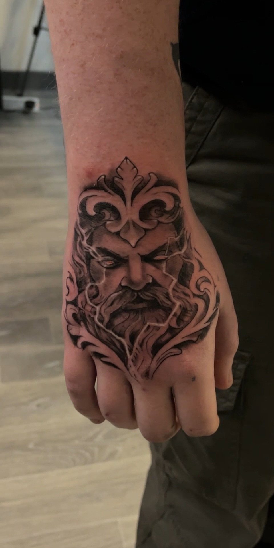 Detailed black and grey realism tattoo of a bearded man on a hand.