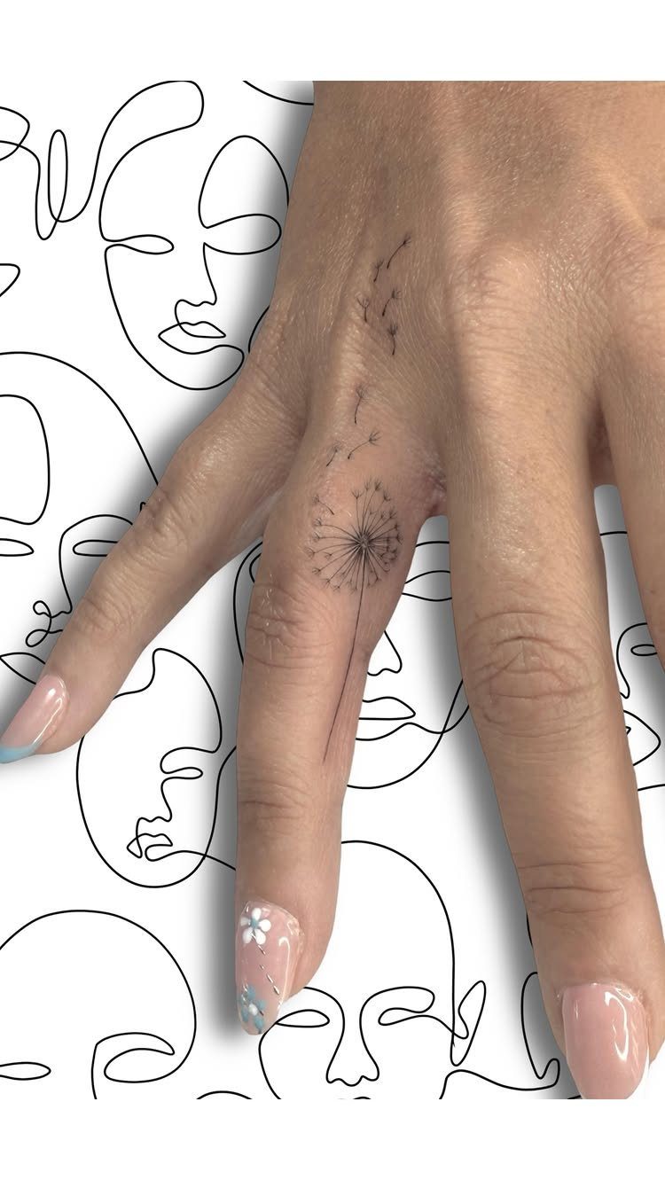 Small dandelion tattoo on a middle finger with manicured nails and line art background