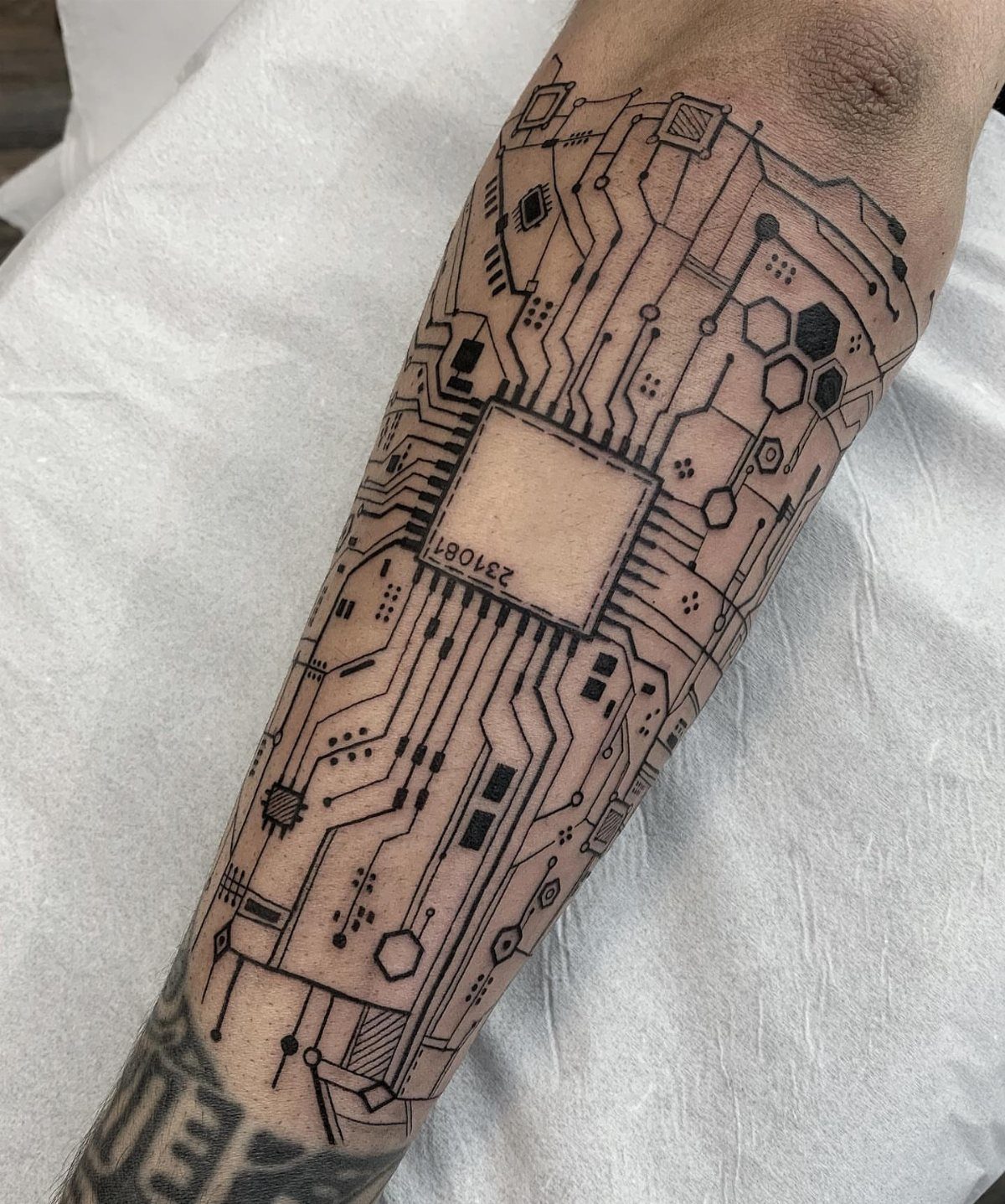 Circuit board tattoo on a person's arm with a central processor chip.