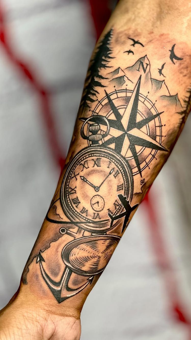 Forearm tattoo featuring a compass rose, pocket watch, and anchor in black ink.