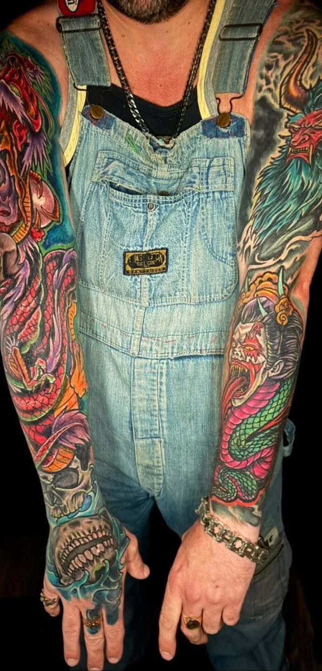 Colorful Japanese style dragon and skull tattoos covering a man's arms and hands.