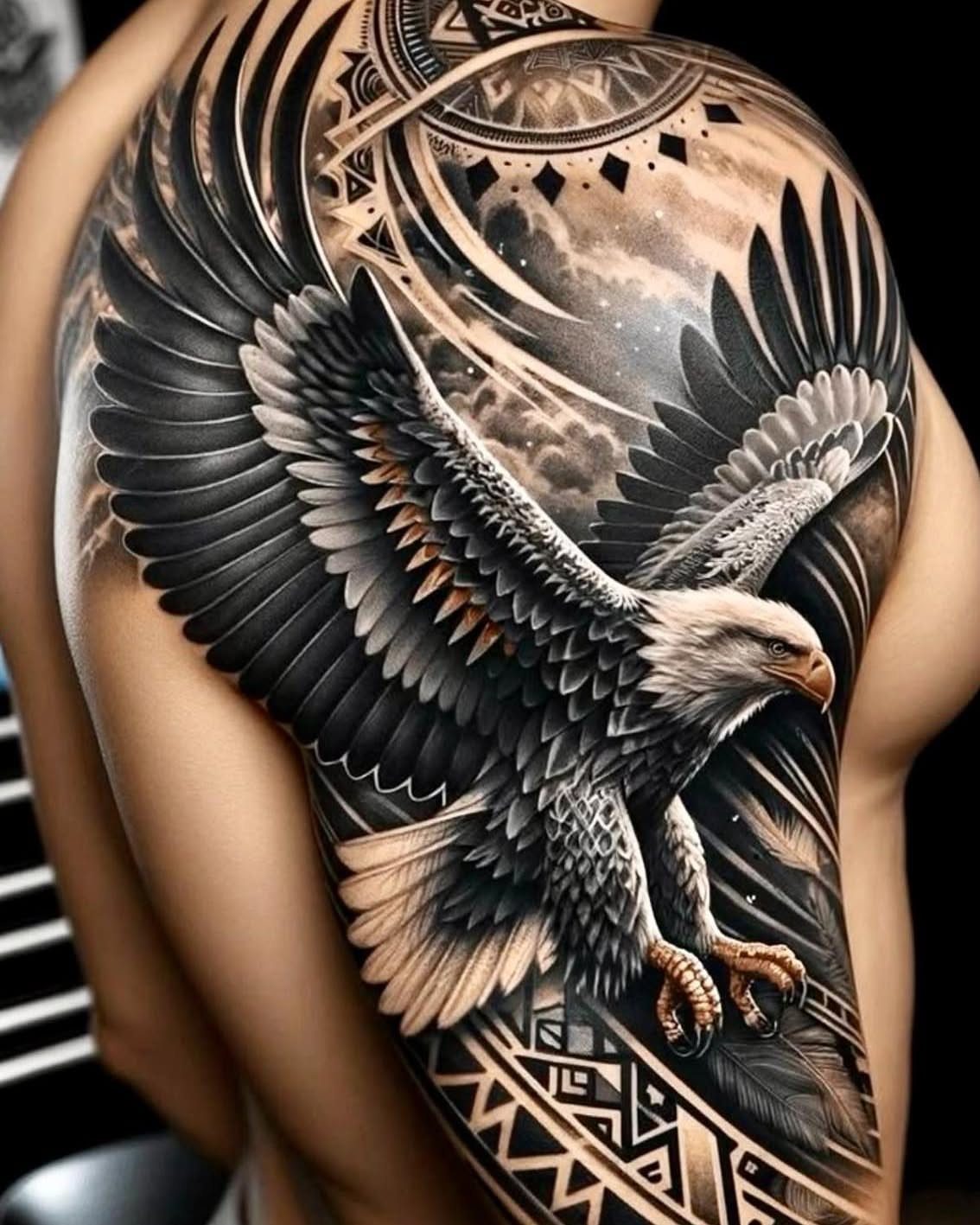 Bald eagle tattoo with outstretched wings and geometric patterns on a man's shoulder.