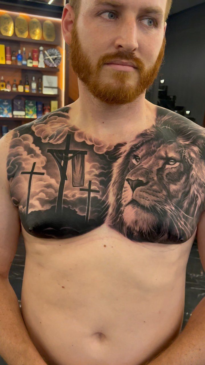 Man with a large chest tattoo featuring a realistic lion and three crosses.