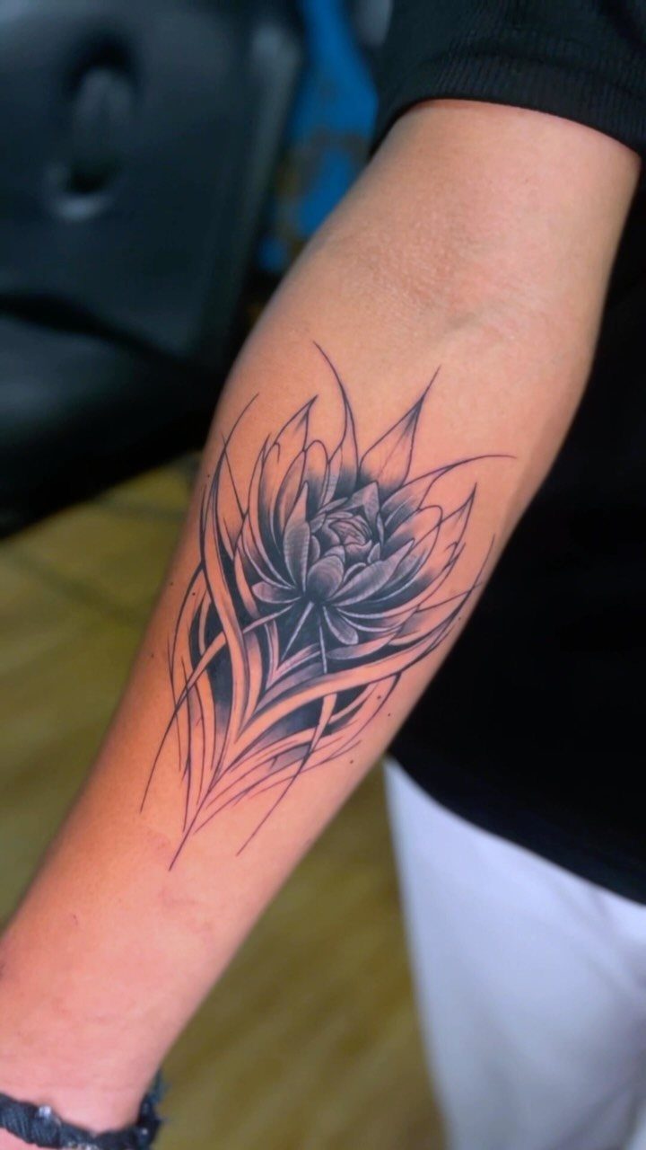 Lotus flower tattoo with sharp petals on a man's forearm in black ink