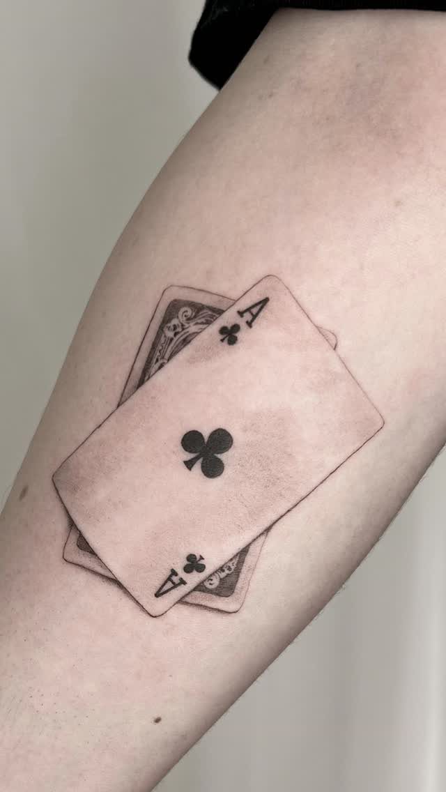 Ace of Clubs playing card tattoo on a person's arm in black ink