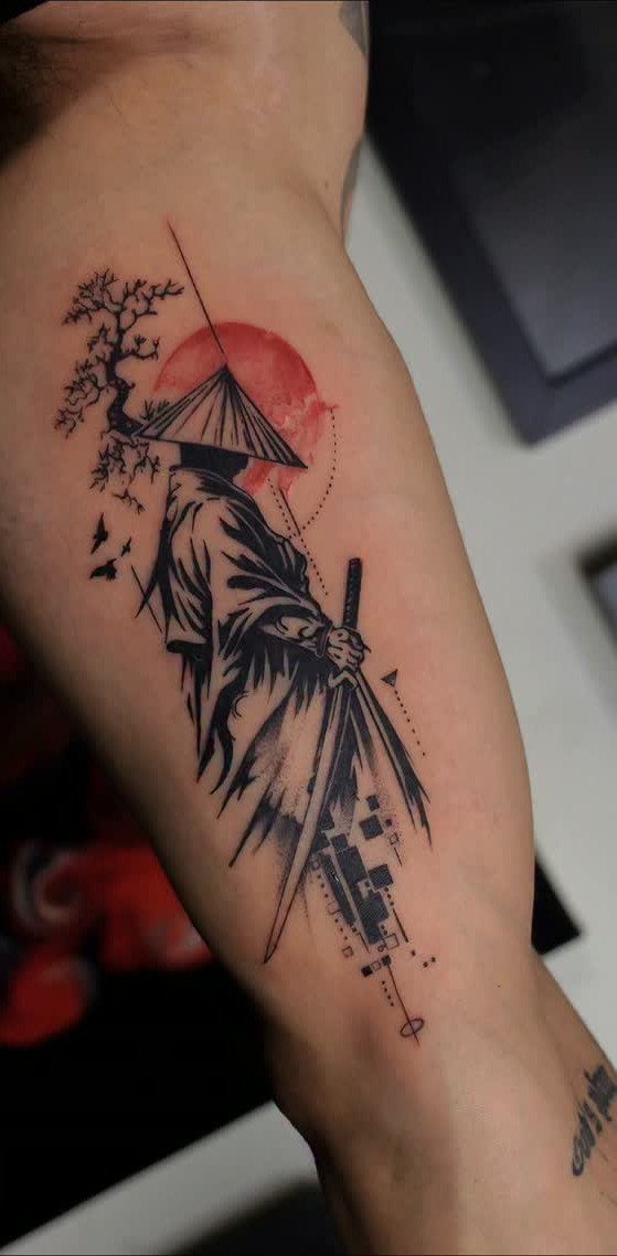 Samurai tattoo on an arm with a red sun and traditional Japanese elements.