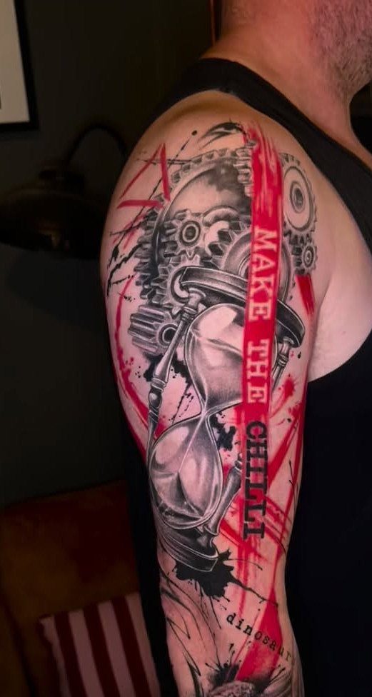 Trash Polka tattoo on a man's arm featuring an hourglass and red abstract splashes.