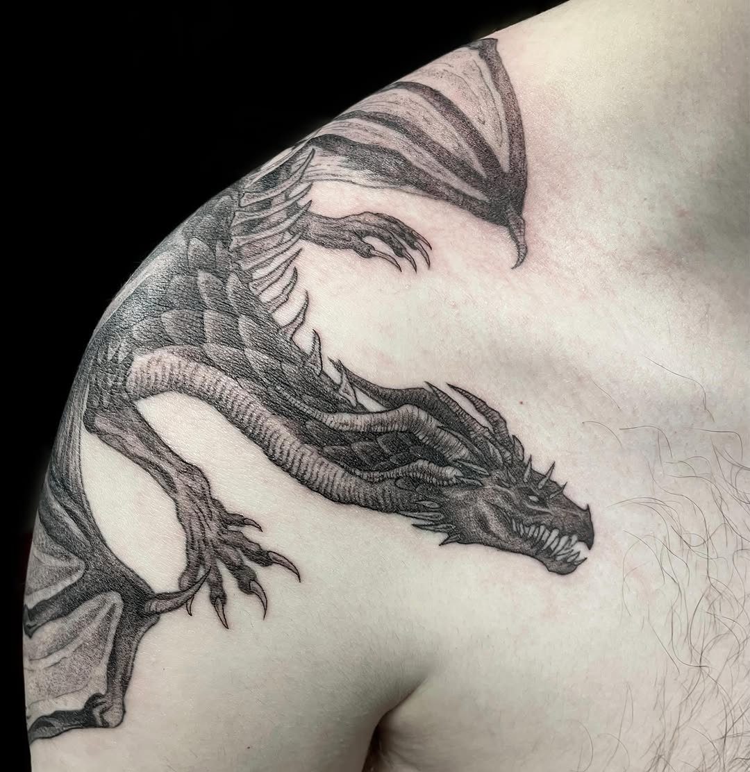 Dragon tattoo with detailed scales and wings on a person's shoulder