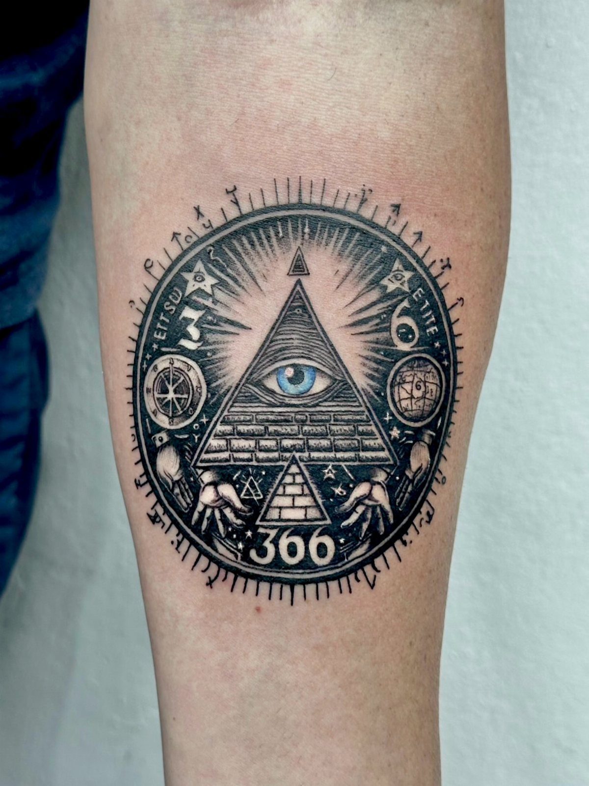 Tattoo of an eye within a triangle with sun rays and occult symbols.