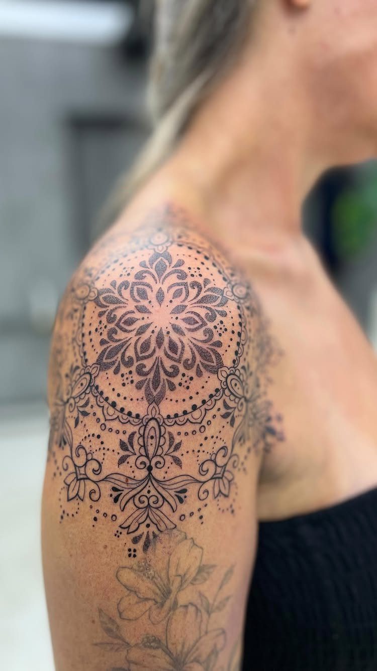 Geometric mandala tattoo with intricate black ink patterns centered on a person's shoulder.